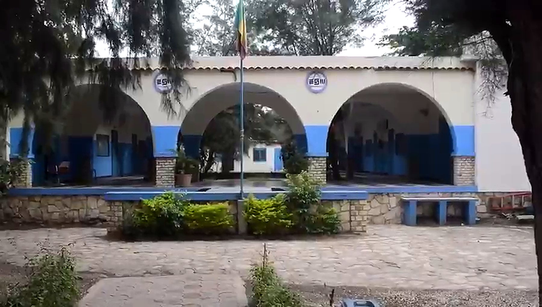 Le préau à arcades du Groupe Scolaire Educazur, avec le drapeau du Sénégal et la cour pavée