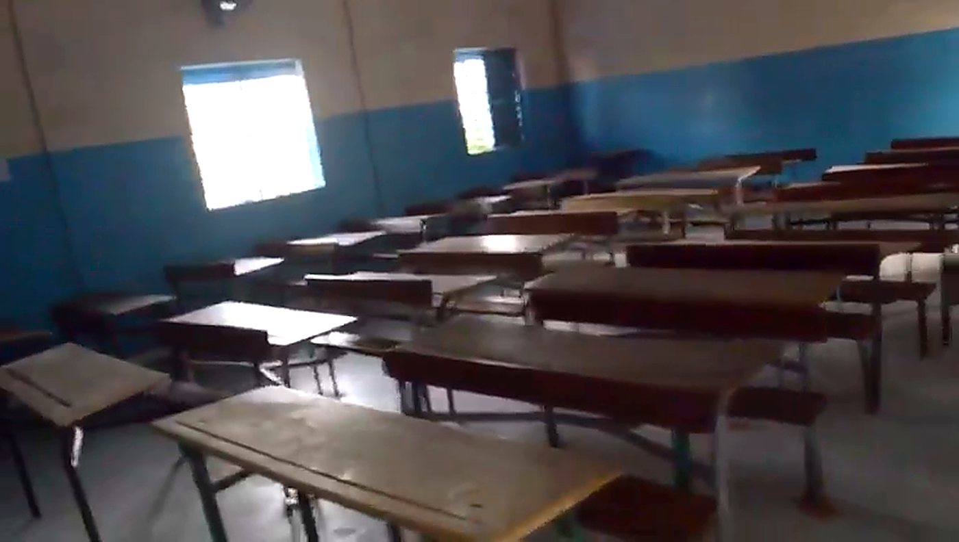 Salle de classe avec tables et bancs en bois, murs peints en bleu et blanc